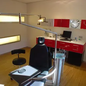 Modern eingerichtetes Zahnarztpraxis-Behandlungszimmer mit Behandlungsstuhl und Arbeitsbereich.